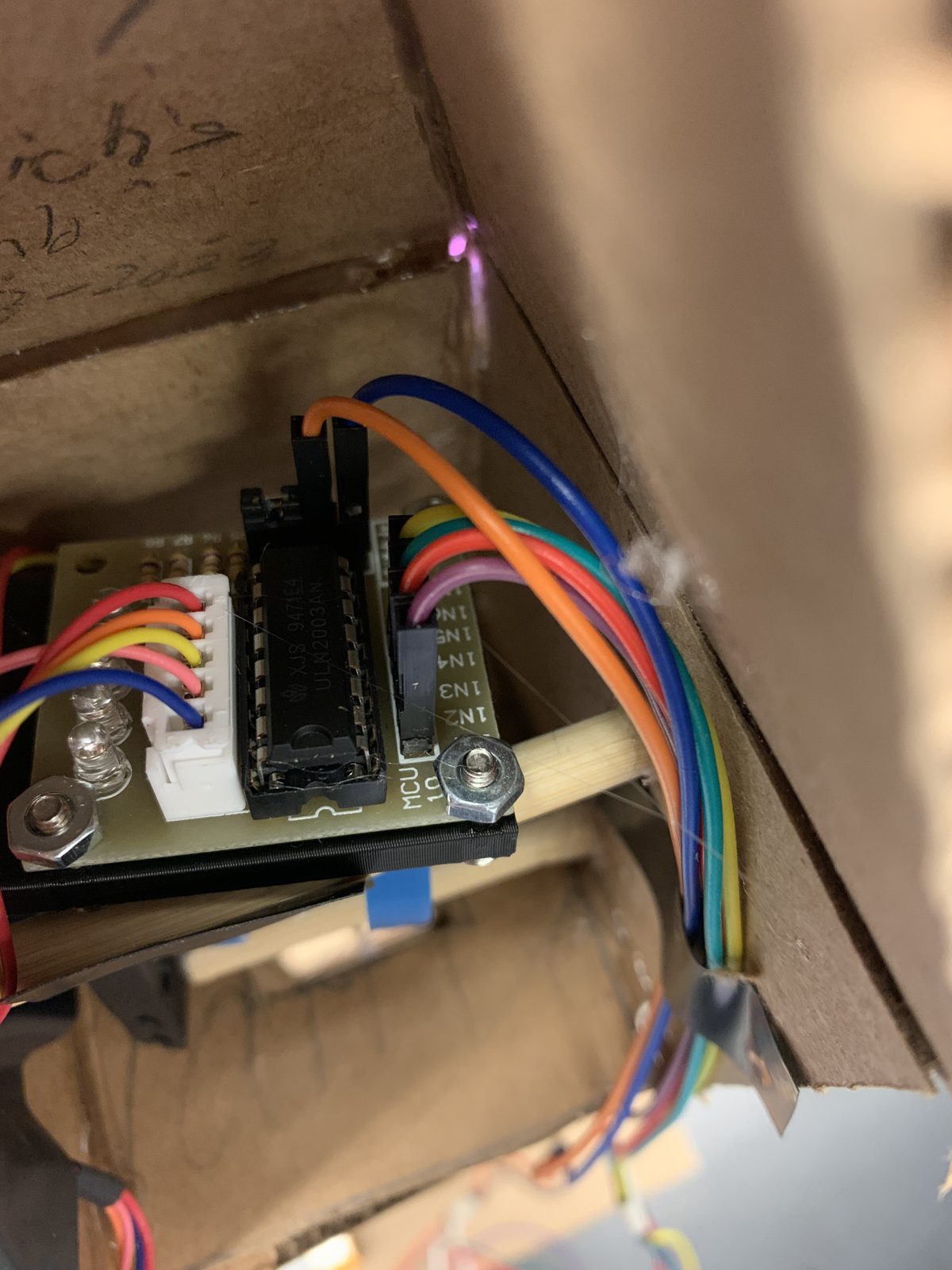 A motor driver board with four indicator LEDs mounted inside the cardboard elevator shaft.